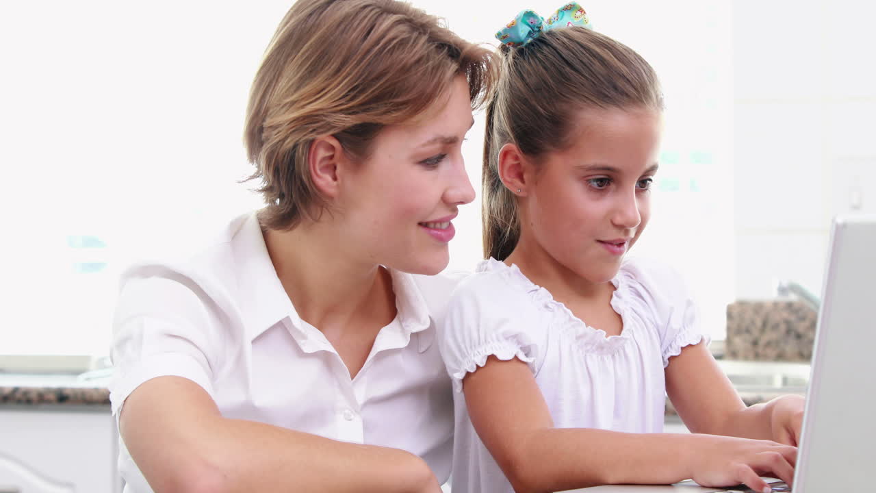 Happy mother and daughter using laptop
