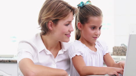 madre y hija felices usando una computadora portátil