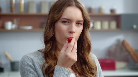 hermosa mujer comiendo fresa en la cocina