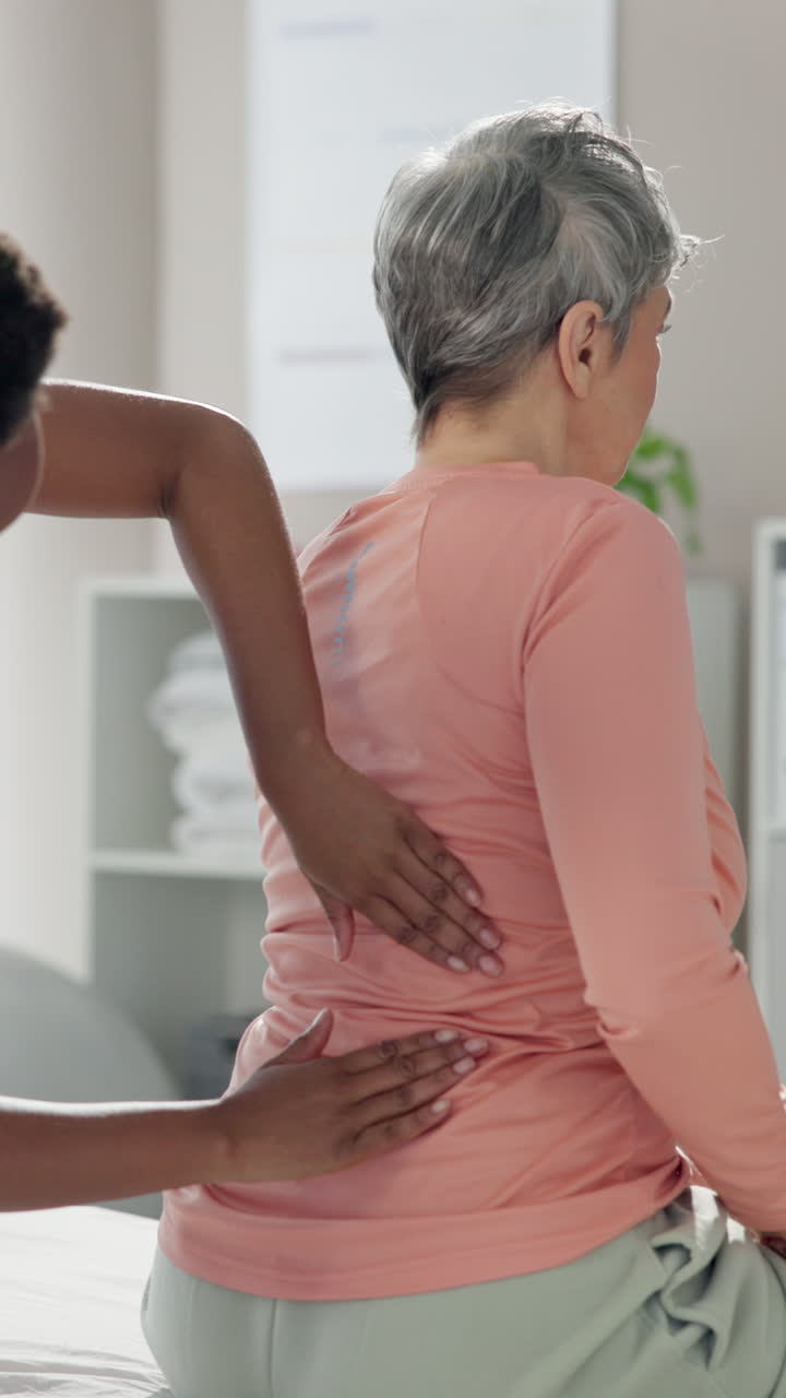 환자의 허리 통증을 치료하는 물리 치료사