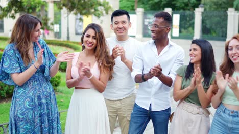 diverse group of smiling people clapping outdoors