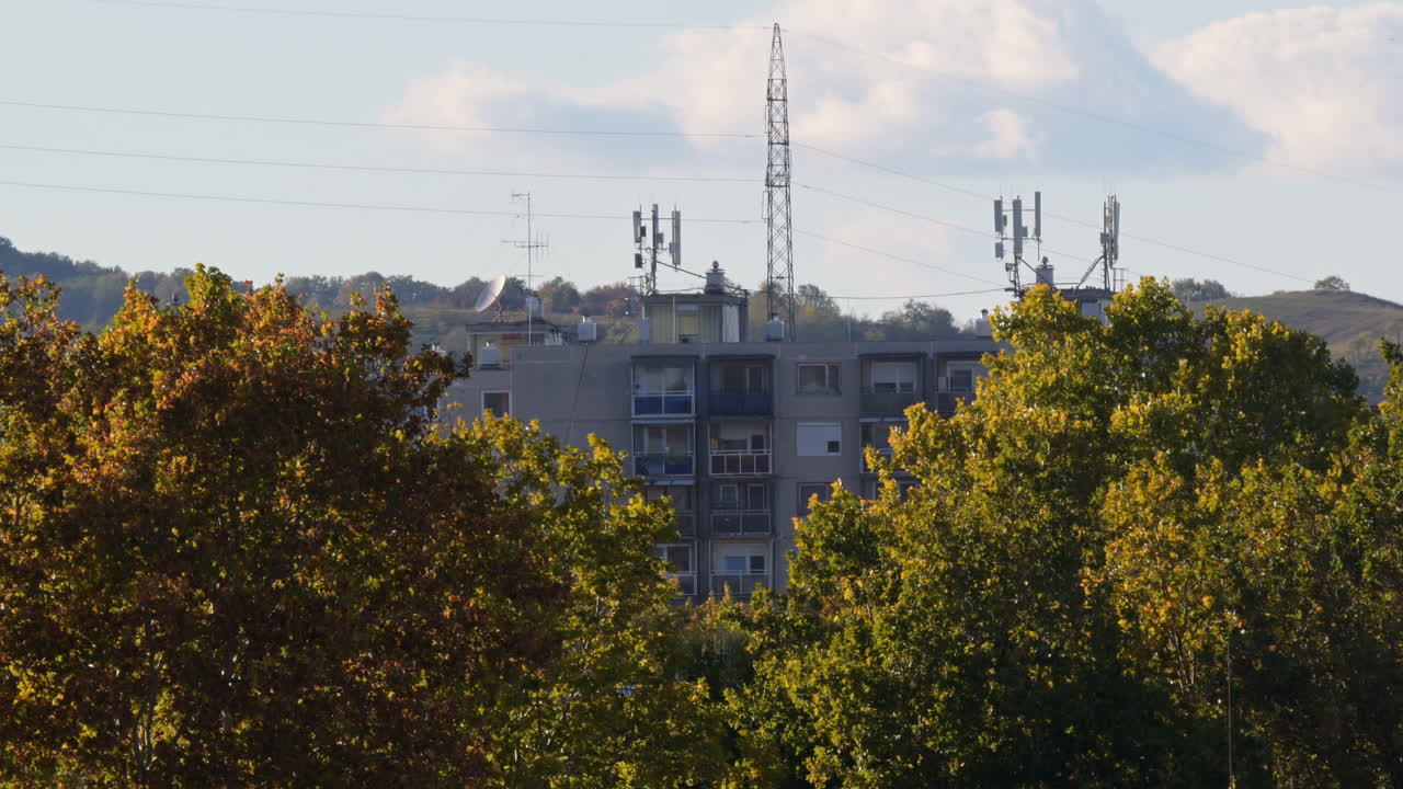 Apartment building behind autumn trees and antennas