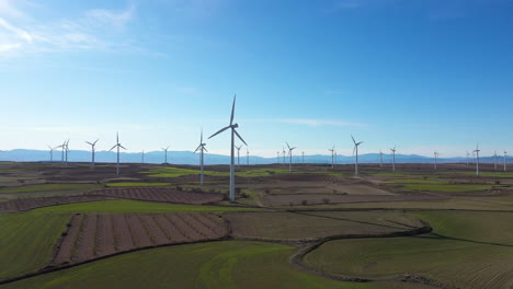 wind turbines in a green field vineyards blue sky aerial shot spain