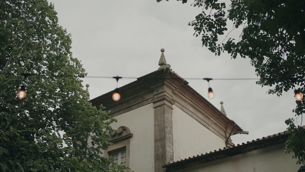 Vista esterna di edificio storico con luci sospese e alberi