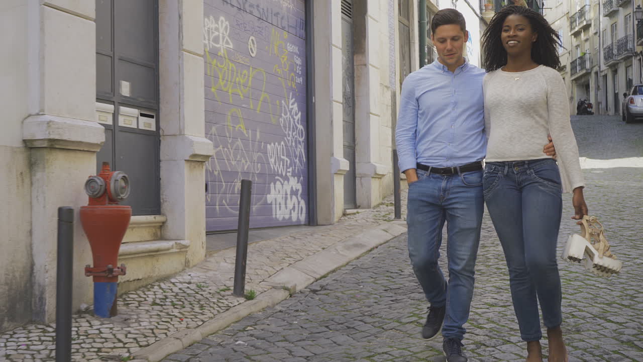 una joven pareja feliz paseando por una calle pavimentada.