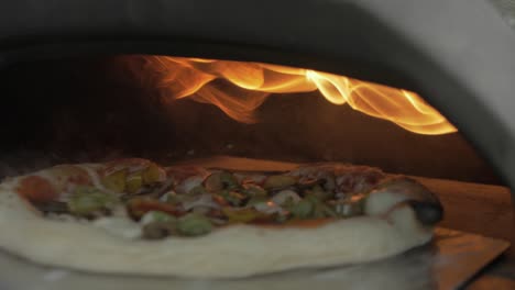 turning a homemade pizza before placing it into pizza oven