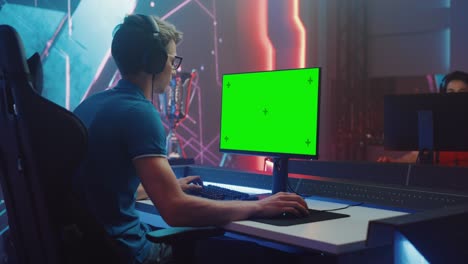 en el campeonato de videojuegos, el jugador de esports profesional juega en la pantalla clave de croma verde de la computadora personal. transmisión en vivo en línea del torneo de ciberjuegos. sala elegante. arco lateral disparo medio
