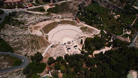 aerial view of roman amphitheater in siracusa, sicily, surrounded by ruins and mediterranean greenery