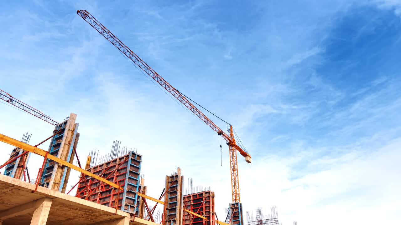 Metal armature on the top of the construction and a crane above. Low angle perspective. Blue sky at backdrop