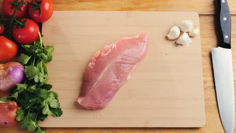raw turkey breast with vegetables and garlic on cutting board