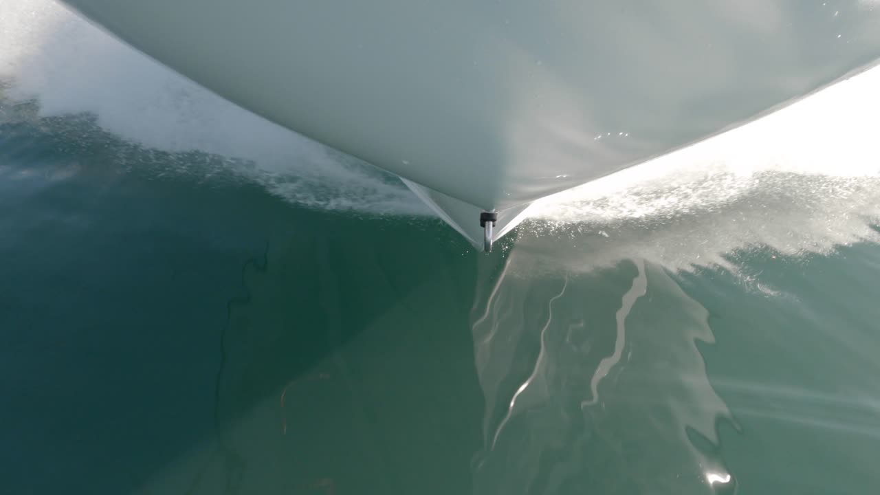 Unique POV angle of boat's bow slicing through jade green water