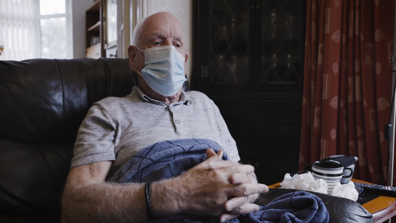 Senior man with mask sitting in armchair
