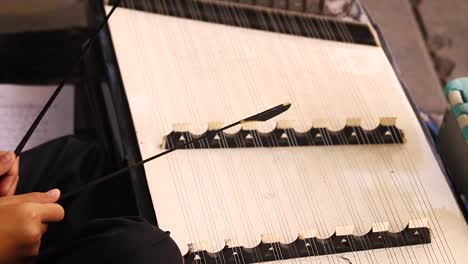 close up of hands playing the khim or dulcimer, a traditional thai classical musical instrument