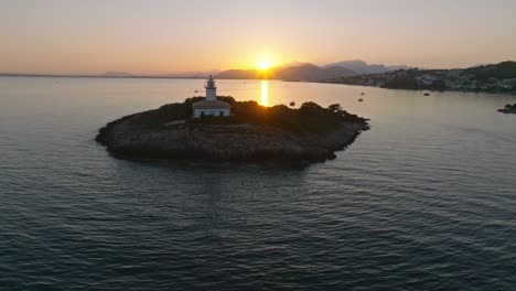 sun sets behind mountains casting golden light across ocean leading to alcanada lighthouse