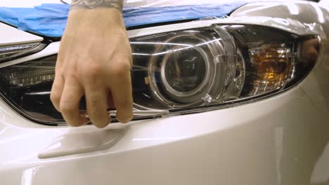 hombre cubriendo el coche con cinta de poliuretano de vinilo. películas para el coche. pegatina película protectora en el faro del coche