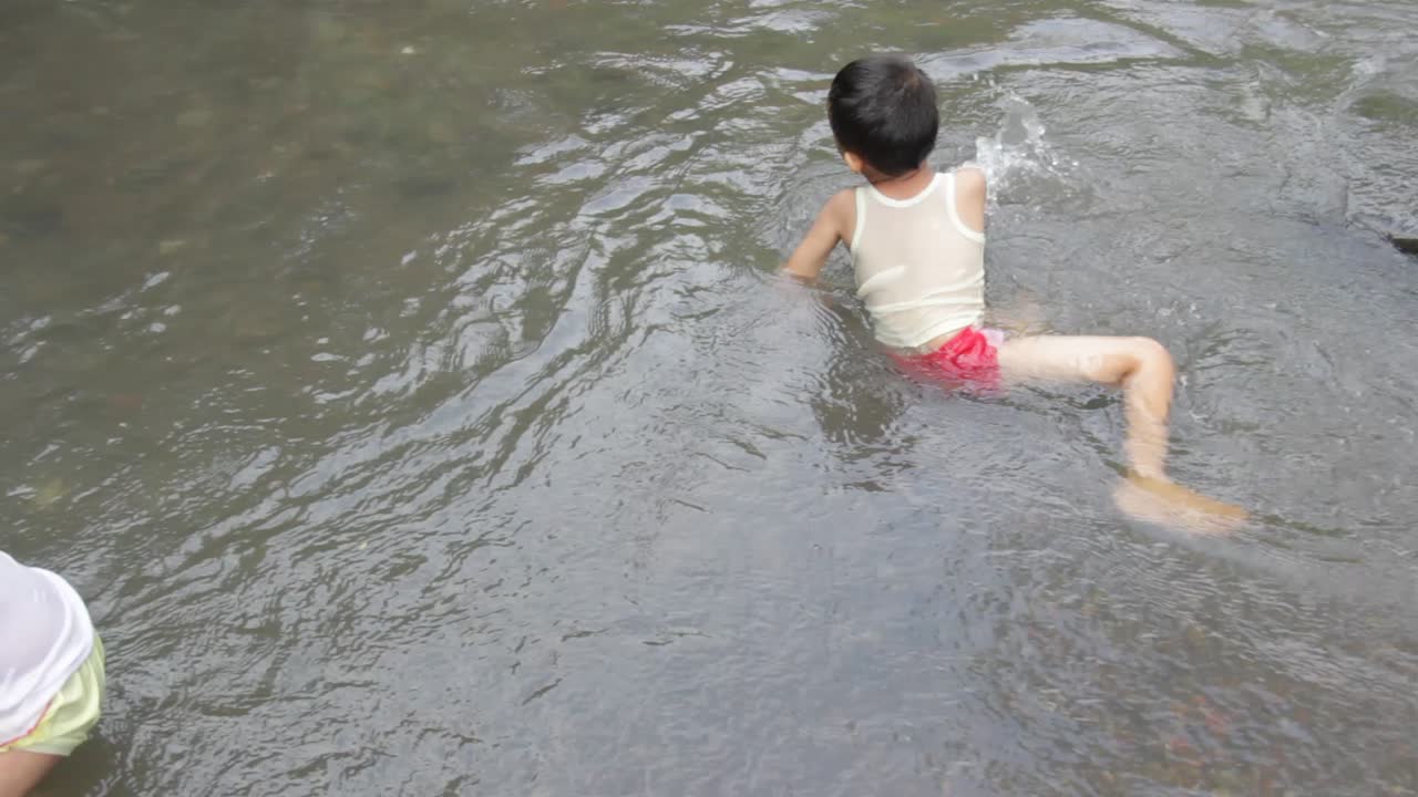 Pasuruan, Indonesia. January 2020, a girl is playing river water with her brother