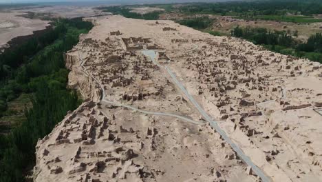 high altitude drone aerial fly jiaohe ruins amidst river valleys in turpan, off road beaten path