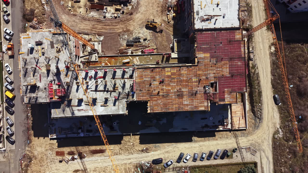 Construction site shows building progress with cranes and machinery working on multiple structures in an urban area during daylight hours