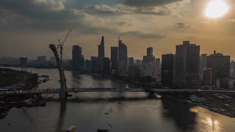classic drone hyperlapse view and establishing shot of saigon river, vietnam from drone with bridge under construction view and modern city skyline at sunset