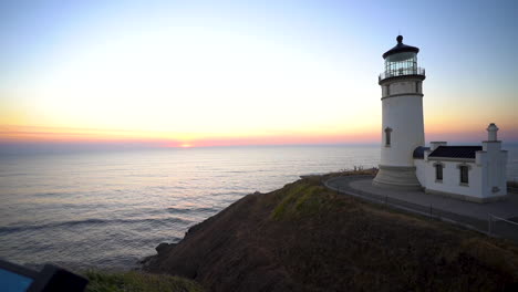 lighthouse tower on top of hill and sunset above pacific ocean on skyline, cape disappointment, american coastline and 19th century landmark, panorama