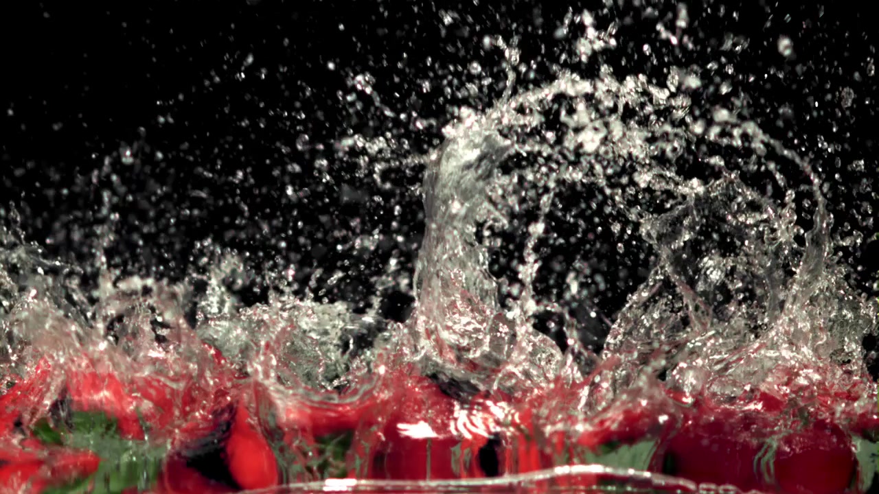 Peperoni rossi freschi che si tuffano nell'acqua al rallentatore