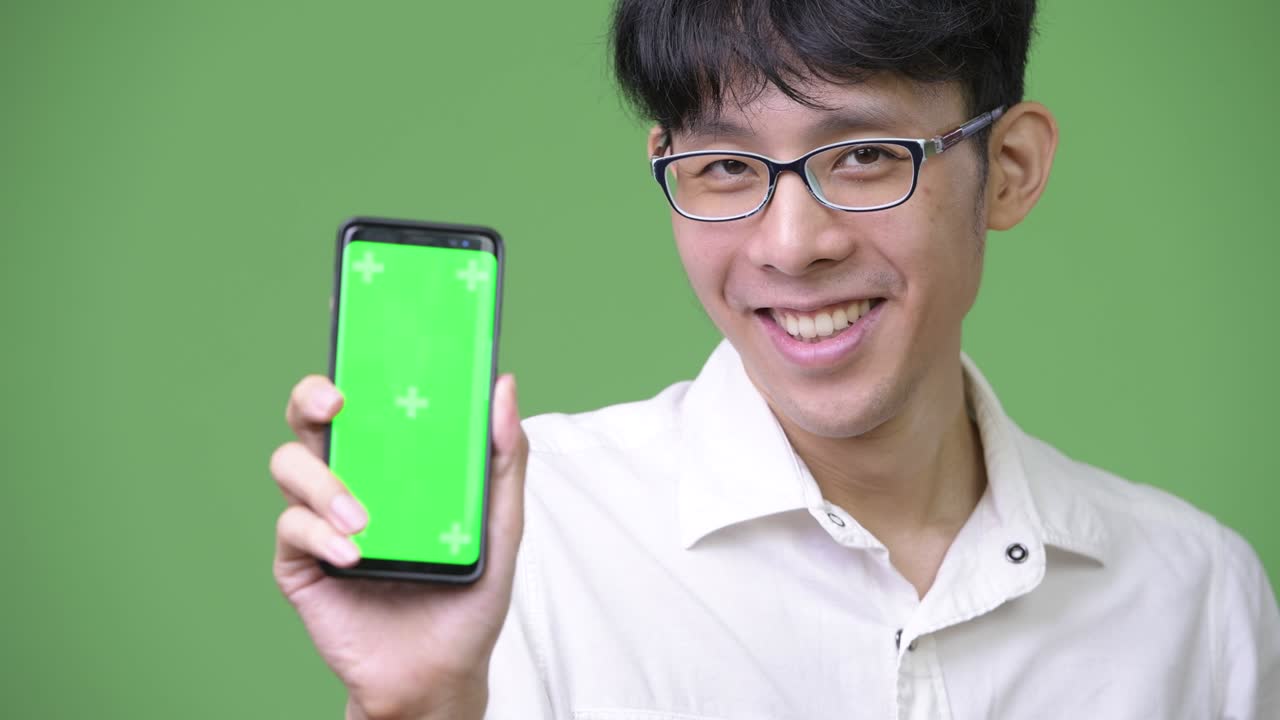 젊은 아시아 사업가 가 카메라 에 전화 를 보여주고 있다