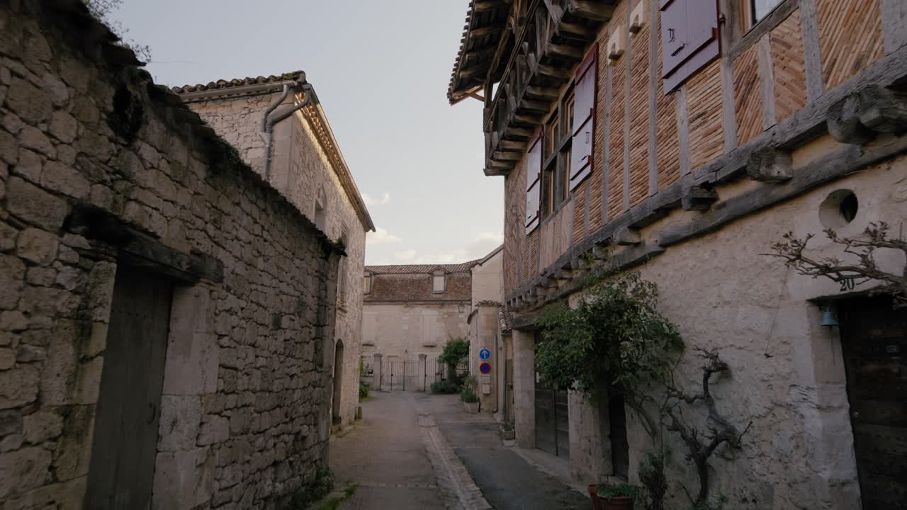 Edifici in pietra e architettura tradizionale a graticcio fiancheggiano una stretta via medievale nella bastide di Issigeac, Dordogna. Carrellata in avanti.