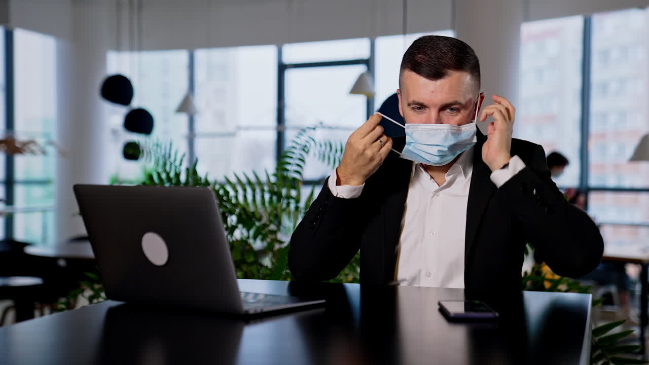 Responsible adult man takes precocious measures to avoid infection. Businessman putting on a mask to work in the office.