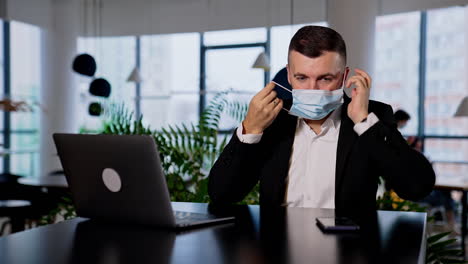 responsible adult man takes precocious measures to avoid infection. businessman putting on a mask to work in the office.