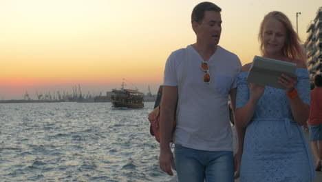 al atardecer, una joven pareja camina por el paseo marítimo en tesalónica, grecia.
