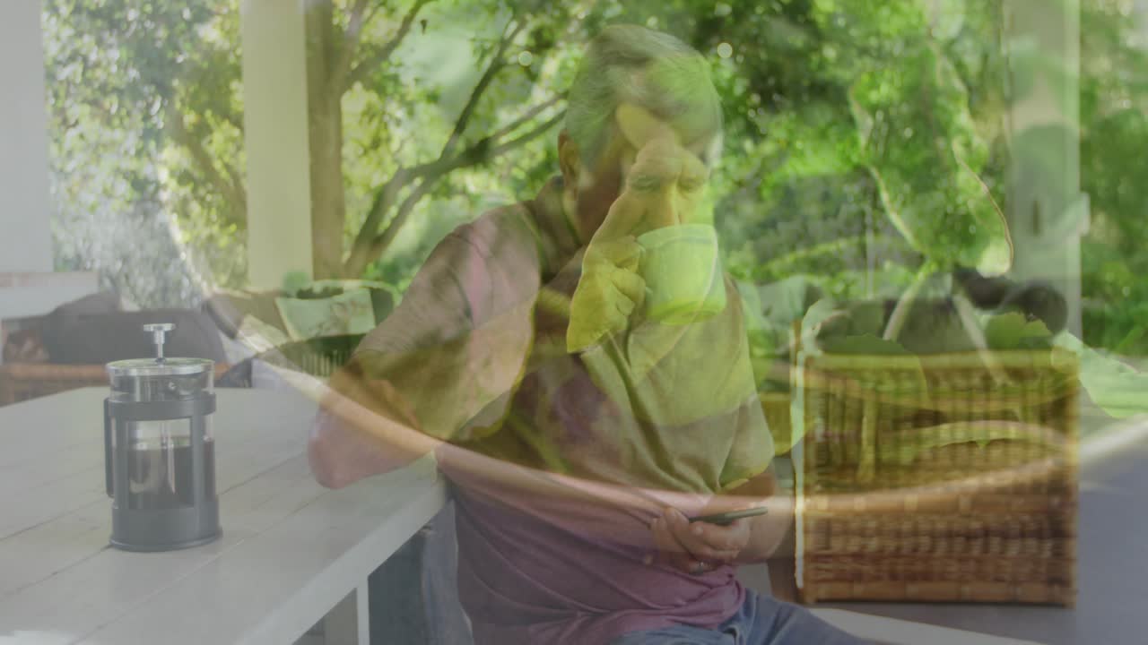 Senior man settling on patio reaching smartphone showing animated icon sipping coffee for tech news