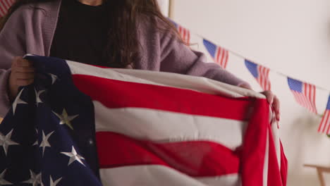 mujer en casa poniendo estrellas americanas y banderas de rayas en el sofá para la fiesta celebrando el 4 de julio día de la independencia