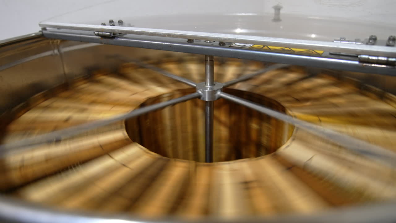 Rotating mechanism working inside the metal barrel. Electric centrifuge machine extracting honey from frames. Close up.