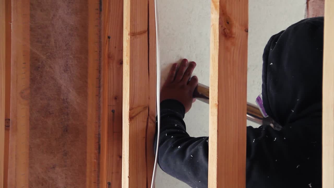 A worker fills a wall with blown-in insulation