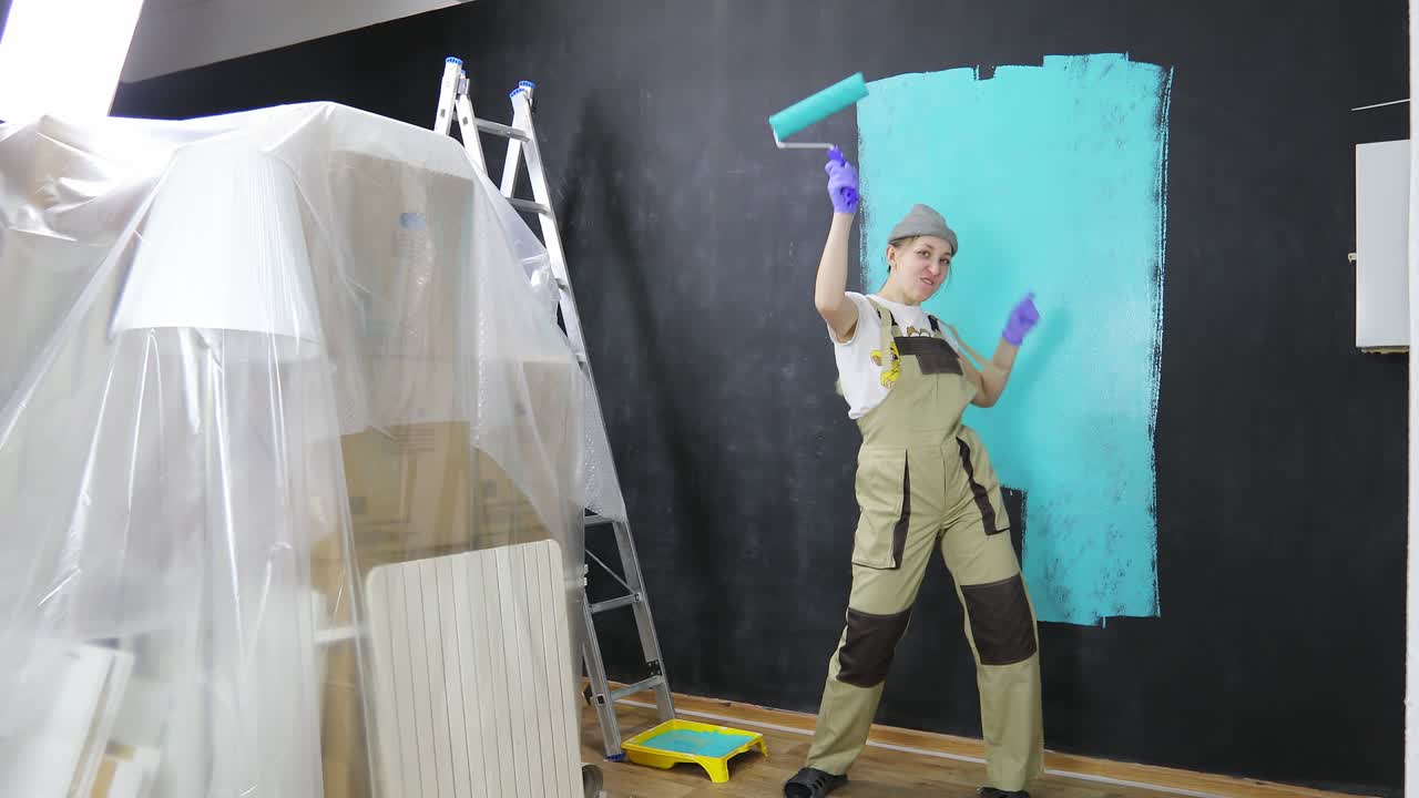 una chica hermosa hace reparaciones en el apartamento y baila.