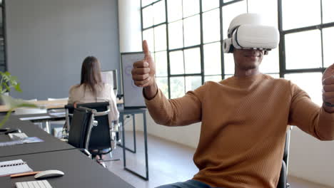 using vr headset, african american man giving thumbs up in modern office workspace