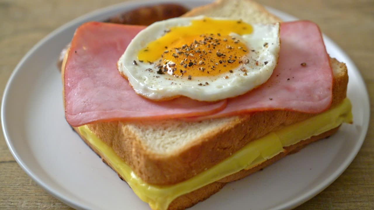 아침 식사로 홈메이드 빵에 구운 치즈를 얹고 햄과 달걀 프라이를 곁들인 돼지고기 소시지