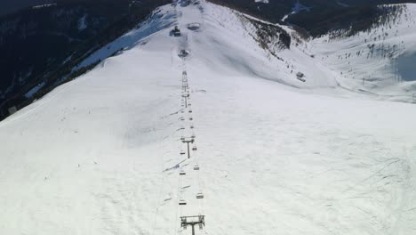 Toma-Aérea-Inclinada-Hacia-Arriba-De-Un-Remonte-Alpino-En-La-Cima-De-Una-Montaña