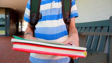 portrait of happy schoolboy standing with books in corridor 4k