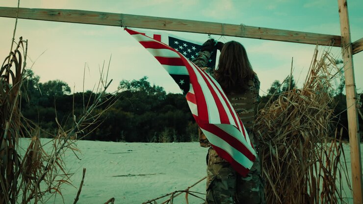 American flag waving on a beach during Memorial Day with a sailor soldier