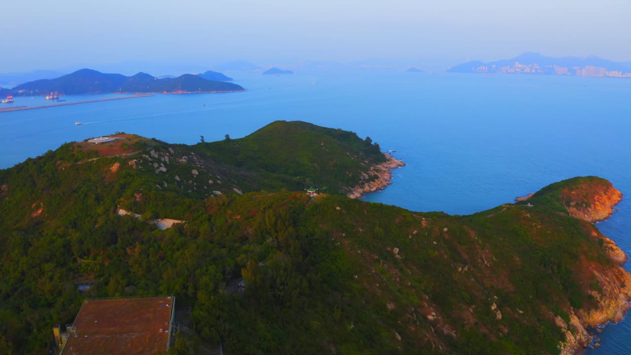 Drone shot traveling forward above an island toward a little Asian observation structure on the peak of one of the hills during the day.