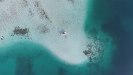 AERIAL-TOP-DOWN-ZOOM-IN-MOTOR-BOAT-IN-MIDDLE-OF-NOWHERE,-CARIBBEAN-SEA-,SHADOWS-OF-BLUES