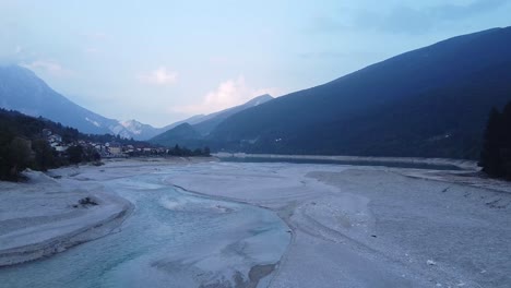 Dry-lake-of-Barcis-in-Italy-Alps,-person-passing-on-bridge,-aerial-fly-back-view