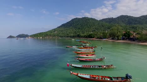 slowly fly over longtail boats on empty beach at close up thailand