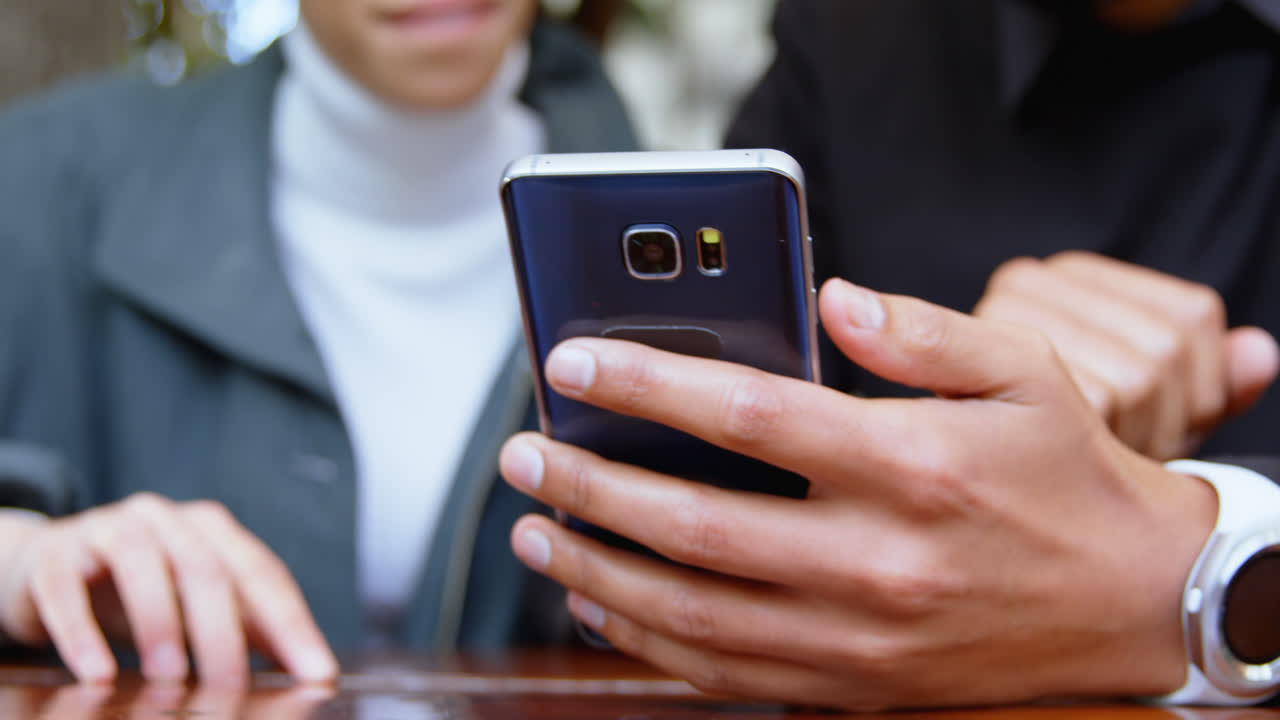 커플이 야외 카페 4k에서 휴대전화를 사용합니다.