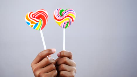 hand hold rainbow heart shape lollipop