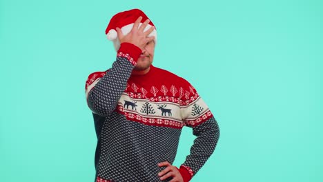 upset man in christmas red sweater making face palm gesture, feeling bored, disappointed, bad result