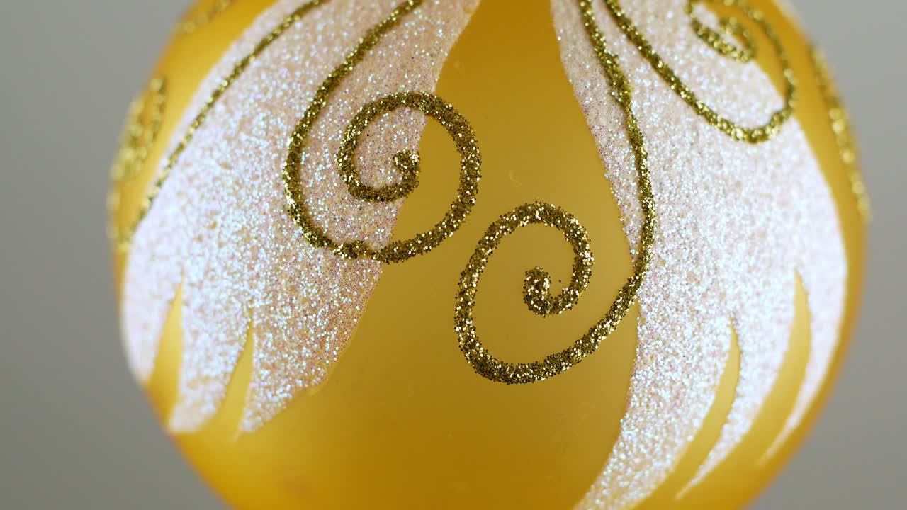 золотая рождественская мяч-игрушка, поворачивающаяся и возвращающаяся в светящемся свете на темно-зеленом фоне.