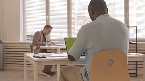 man typing on computer with greenscreen