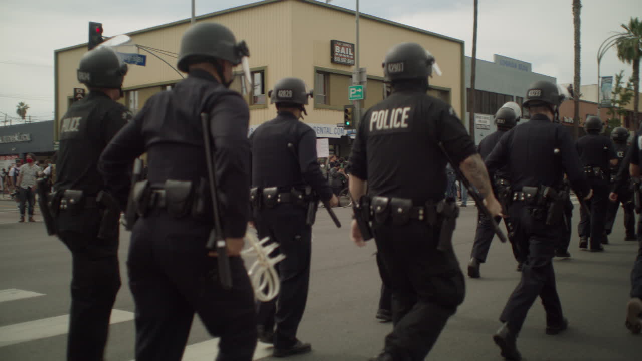 A group of Police offers running to a crime scene in the middle of the street during a protest by the city hall